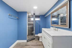 Bathroom featuring vanity, a stall shower, and light wood-style flooring