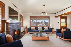 Living room with suspended lighting, ornamental molding, and a fireplace
