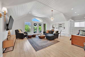 Living room featuring light wood-style floors, french doors, vaulted ceiling, wooden ceiling, and ornamental molding