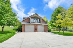 View of ADU featuring a front lawn, a balcony, brick siding, and driveway