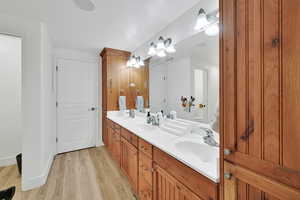 Bathroom with double vanity and light wood-style flooring