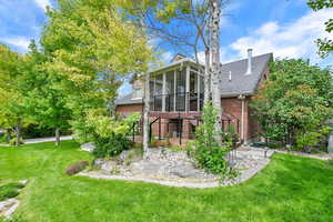 Side of ADUfeaturing brick siding, a sunroom, a yard, and a shingled roof