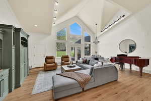 Living room with french doors, light wood-style floors, and a high ceiling