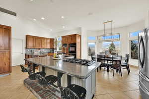 Kitchen with a kitchen bar, a kitchen island with sink, black appliances, dark stone countertops, and wood finish cabinets