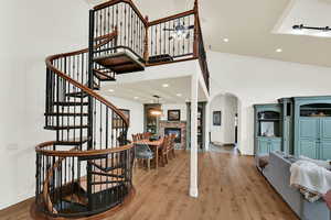 Foyer with a high ceiling, ornamental molding, light wood-style floors, recessed lighting, and a fireplace