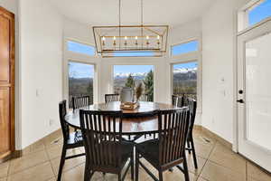 Dining space with a mountain view, light tile patterned floors, a high ceiling, and suspended lighting