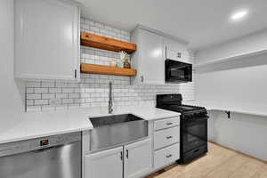 Kitchen featuring black appliances, open shelves, white cabinets, and light wood-style flooring