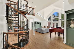 Staircase with a high ceiling, wood finished floors, and recessed lighting