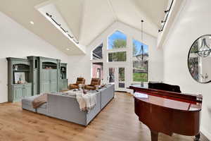 Living room featuring french doors, light wood-style floors, a high ceiling, and a chandelier