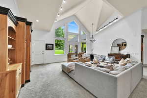 Living room featuring light colored carpet and high vaulted ceiling
