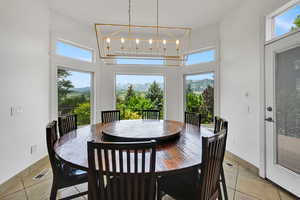 Dining space with light tile patterned floors, a high ceiling, healthy amount of natural light, a mountain view, and a chandelier