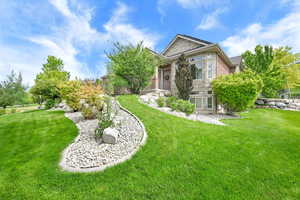 View of property exterior with a yard, stone siding, and brick siding