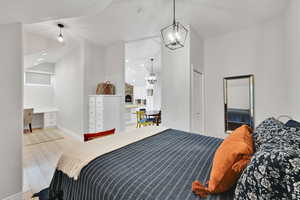 Bedroom featuring built in study area, wood finished floors, and high vaulted ceiling