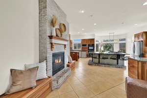 Living area with light tile patterned flooring, a brick fireplace, healthy amount of natural light, and recessed lighting