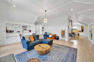 Living area with recessed lighting, lofted ceiling, light wood finished floors, built in shelves, and a chandelier