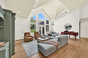 Living room with light wood-style flooring, a high ceiling, recessed lighting, and french doors