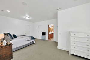 Bedroom with light colored carpet and connected bathroom