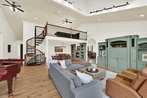 Living area with a ceiling fan, ornamental molding, light wood finished floors, a high ceiling, and recessed lighting