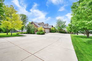 View of side of property featuring a lawn, concrete driveway, and an attached garage