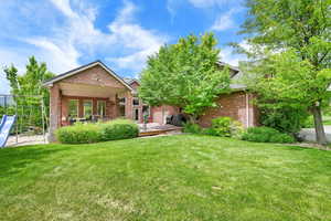 Rear view of property with brick siding, a lawn, and a deck