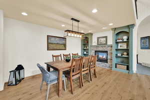 Dining room with light wood-type flooring, a fireplace, built in shelves, and recessed lighting