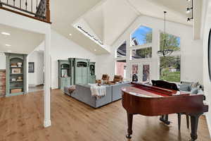 Living area featuring a high ceiling, light wood-style floors, built in shelves, french doors, and arched walkways