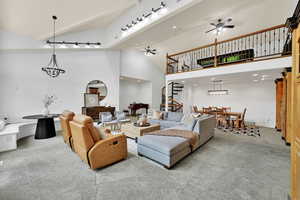 Living area featuring ceiling fan, carpet floors, stairs, high vaulted ceiling, and recessed lighting