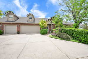 View of side of house with concrete driveway, brick siding, a shingled roof, 3 car garage, and side door