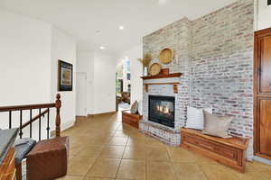 Living area with light tile patterned floors, a brick fireplace, recessed lighting, arched walkways, and brick wall