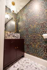 Powder room with wallpapered walls and vanity