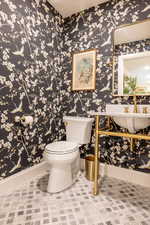Powder room with wallpapered walls and light tile patterned flooring