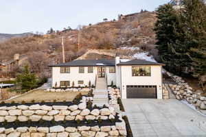 View of front of home with heated stairs and heated driveway, stucco siding, and a chimney