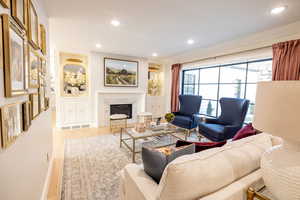 Living room with wood finished floors, a premium fireplace, and recessed lighting