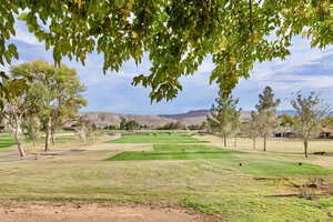 View of community with golf course view, a lawn, and a mountain view