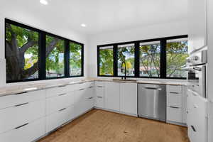 Kitchen with white cabinets, modern cabinets, appliances with stainless steel finishes, light stone countertops, and recessed lighting