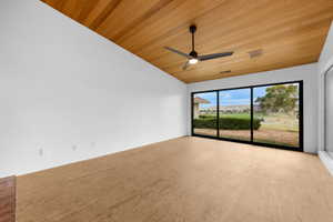 Empty room with lofted ceiling, wooden ceiling, and ceiling fan