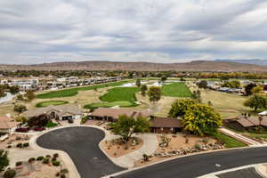 Aerial view of residential area featuring a mountainous background and a golf course