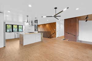 Kitchen with white cabinetry, modern cabinets, light stone countertops, appliances with stainless steel finishes, and brick wall