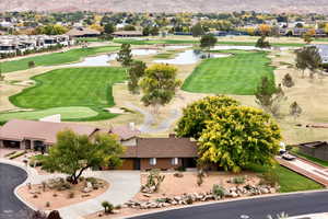 Aerial view of property's location featuring a golf club, a water and mountain view, and nearby suburban area