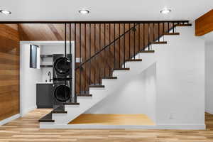 Stairs featuring wood finished floors, stacked washer / drying machine, and recessed lighting