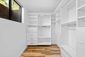 Walk in closet with light wood finished floors