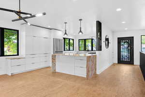 Kitchen with modern cabinets, white cabinetry, decorative light fixtures, high end fridge, and recessed lighting