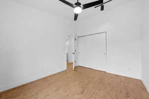 Unfurnished bedroom with wood finished floors, a closet, and a ceiling fan