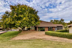 View of front of house with brick siding, a front yard, and roof with shingles