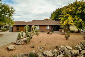Ranch-style house with driveway, brick siding, a shingled roof, and a chimney