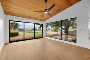 Unfurnished sunroom with ceiling fan, golf course view, and vaulted ceiling