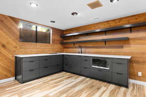 Kitchen featuring gray cabinets, modern cabinets, open shelves, light wood-style flooring, and wood walls