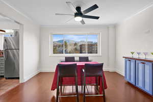 Dining space with ornamental molding, a mountain view, dark wood-type flooring, and a ceiling fan