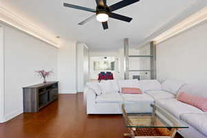 Living room featuring wood finished floors, ceiling fan, and crown molding