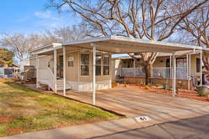 View of side of property featuring covered porch, driveway, a yard, and a carport